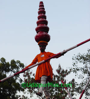 Man walking on rope after putting eight pots on his head.